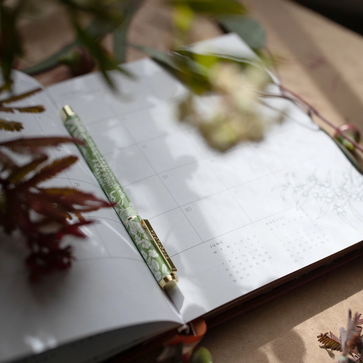Typoflora Sage Botanical rollerball pen resting on an open planner